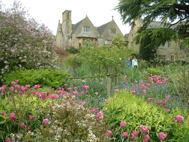 Cotswold gardens with house and couple walking through wildflower garden