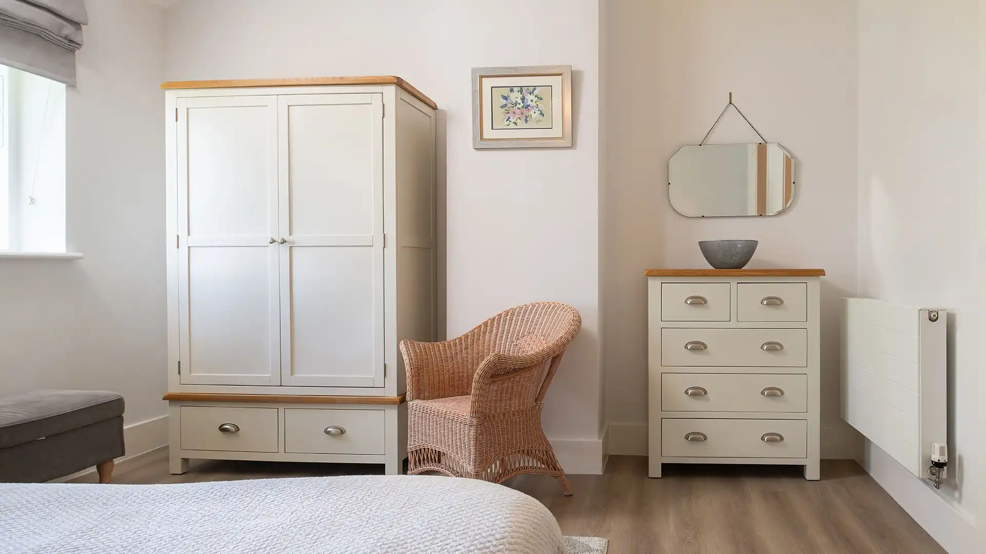 This tranquil space has a wardrobe, chest of drawers and bedside tables and a reading chair
