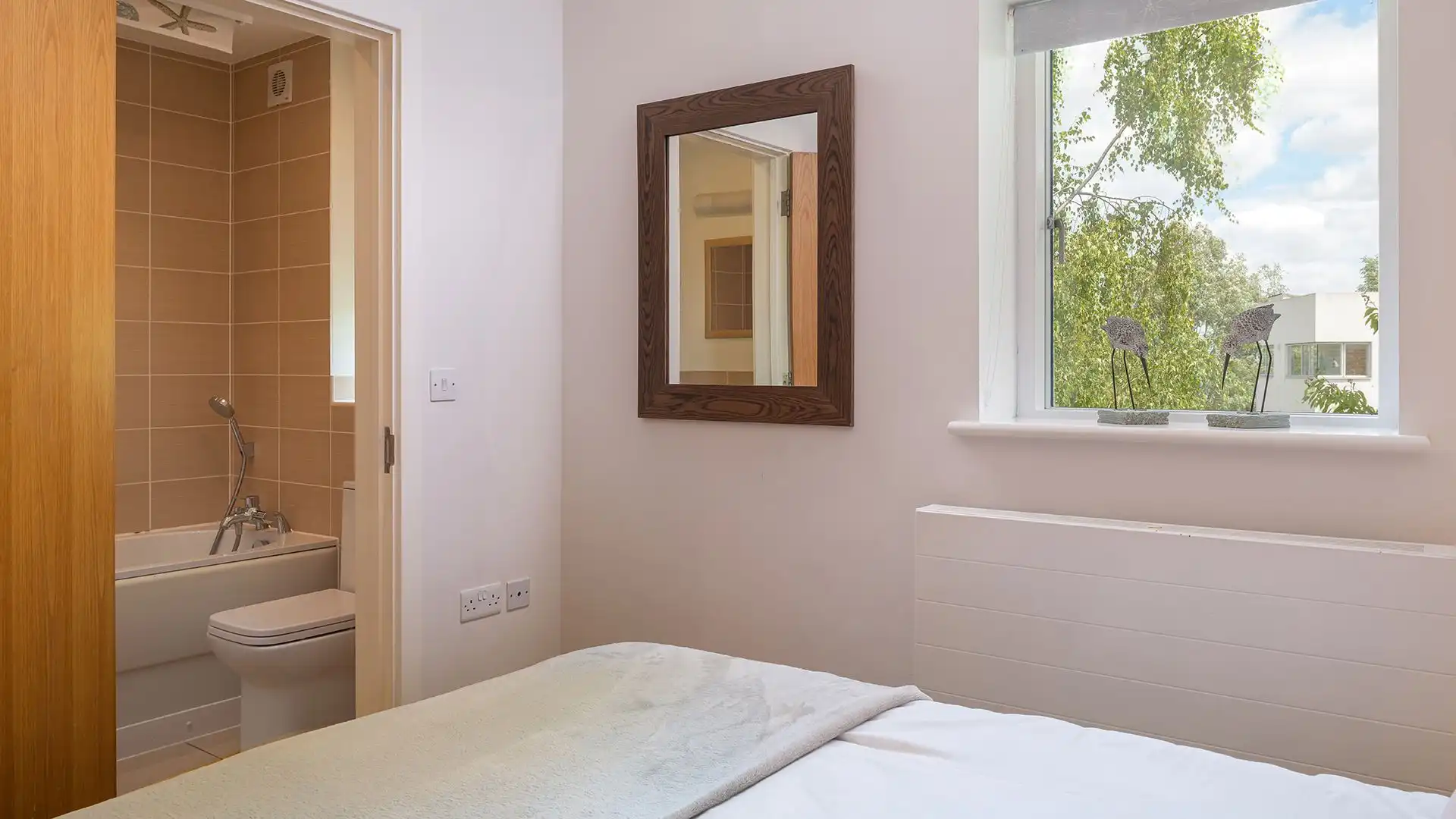 Matching the style of the other en-suite, there is a bath with a shower over, WC and basin