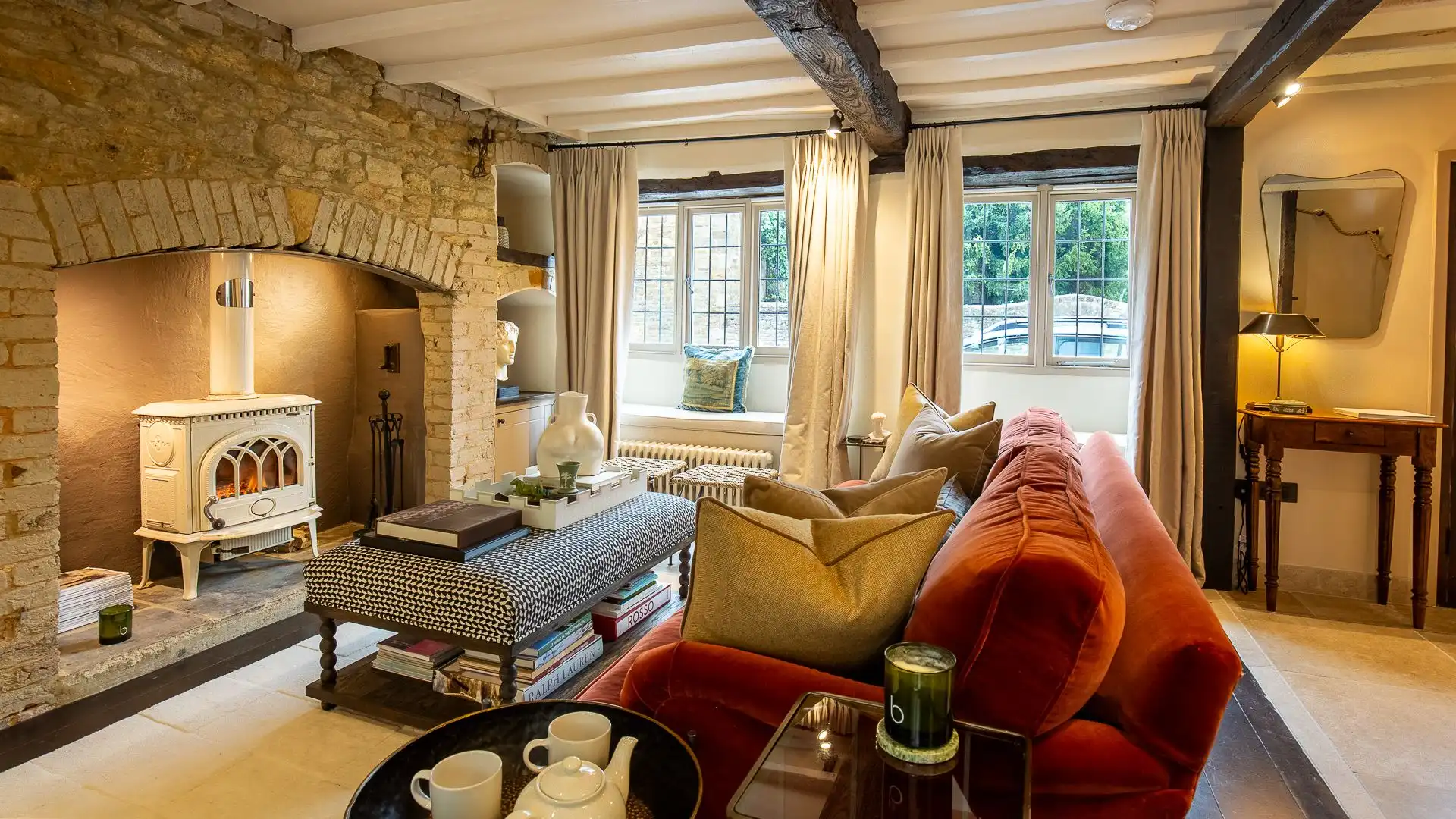 Wooden beams above match the flooring and a sumptuous sofa adds a pop of colour. 