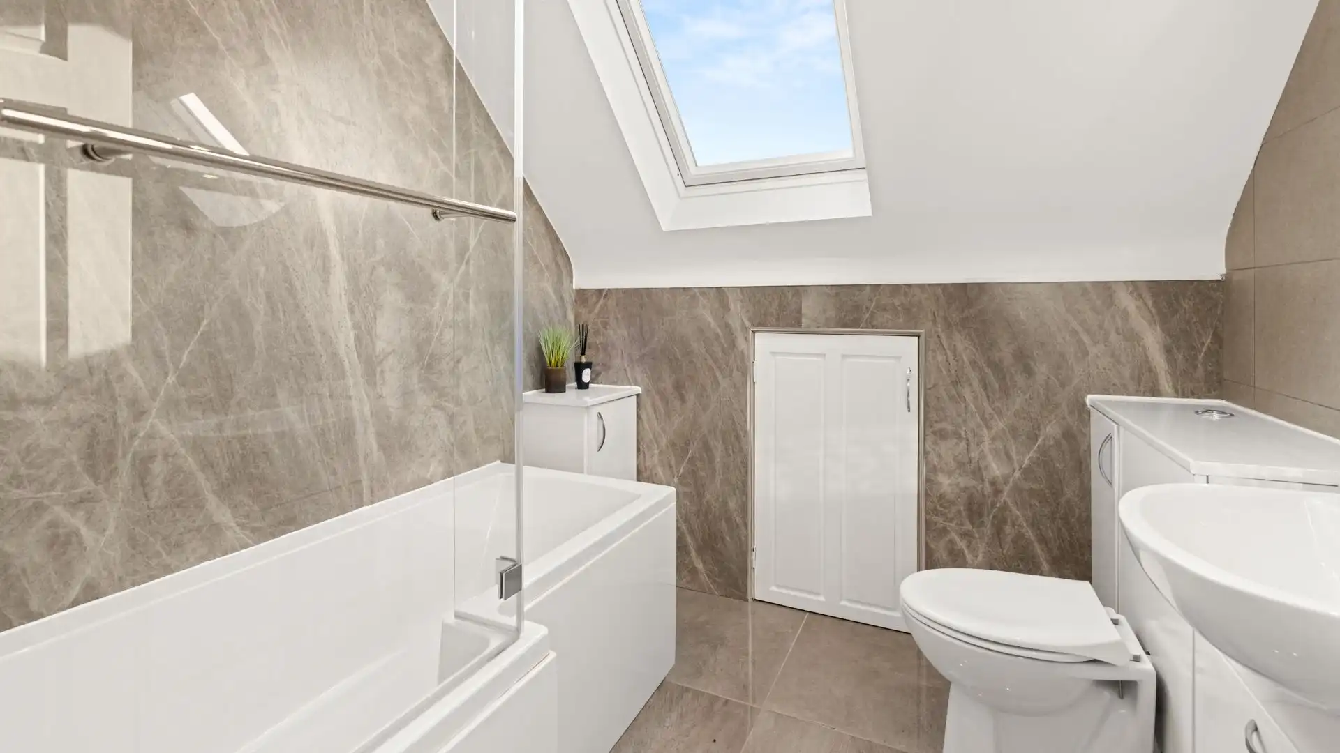 The bathroom has a P-shaped bath with a rainfall shower over, WC and basin.
