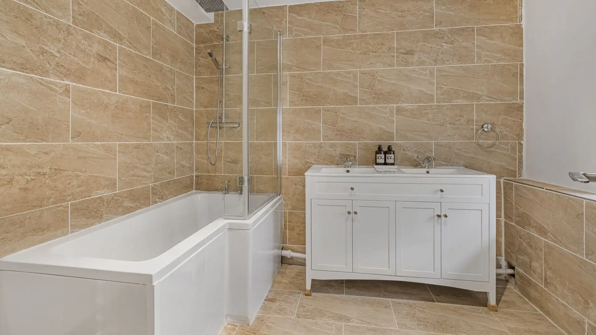 This bathroom has a shower over the bath and a his and her basin.
