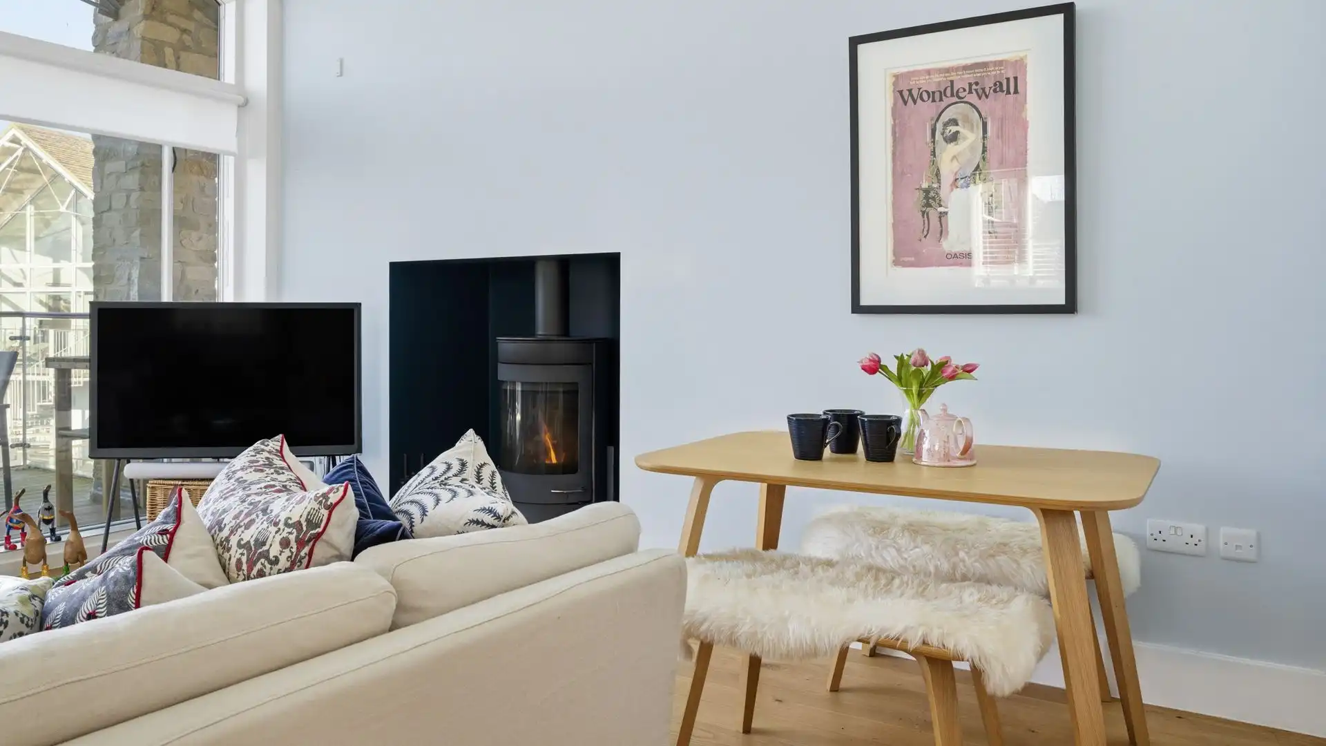The dining area seats four, and the comfortable living space features a corner sofa, Smart TV, and woodburning stove.