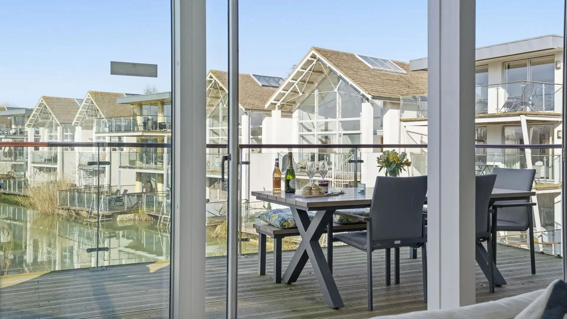 The balcony is furnished with a table and chairs and bench and a coal barbecue.