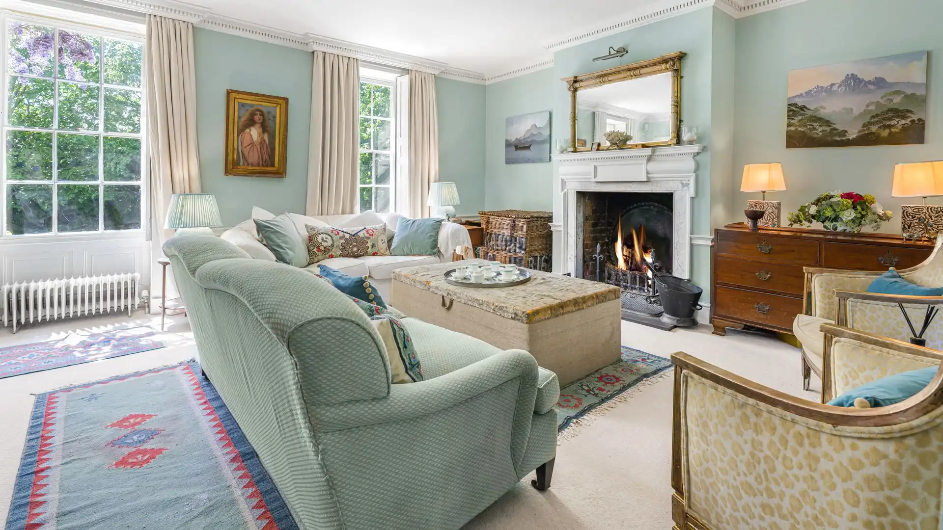 Elegant formal drawing room with sofa seating, log fireplace with marble surround and piano. 