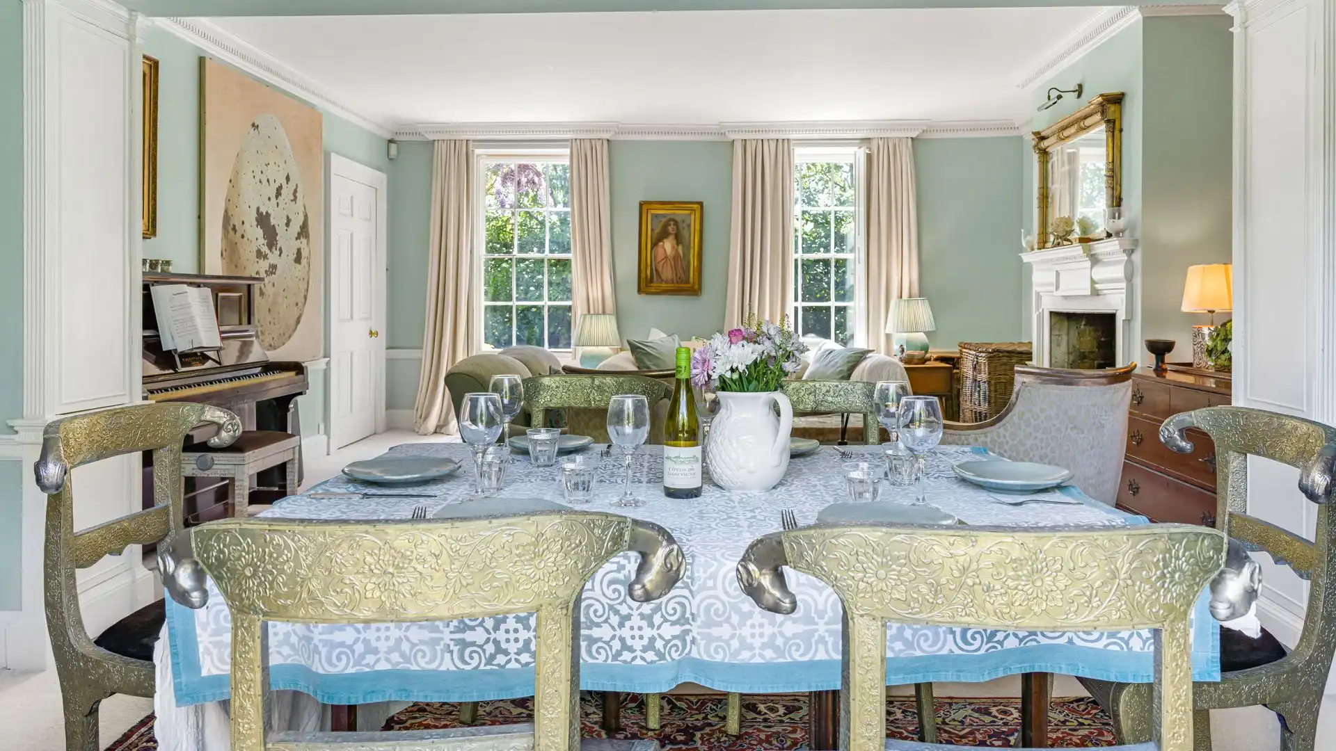 A dining table overlooks the beautiful gardens through French doors.